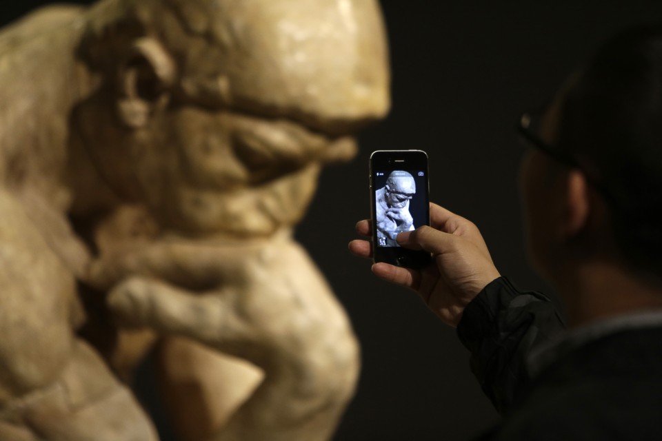 A visitor takes a picture of the sculpture "The Thinker" by French artist Auguste Rodin at the National Museum of China in Beijing November 28, 2014. A total of 140 original works created by Rodin, a 19th century sculptor, were on display from Thursday, including The Thinker, The Age of Bronze, Monument to Balzac and other representative works, in Beijing in honour of the 50th anniversary of the establishment of diplomatic relations between China and France, local media reported. REUTERS/Jason Lee   (CHINA - Tags: POLITICS ENTERTAINMENT) - RTR4FWVV